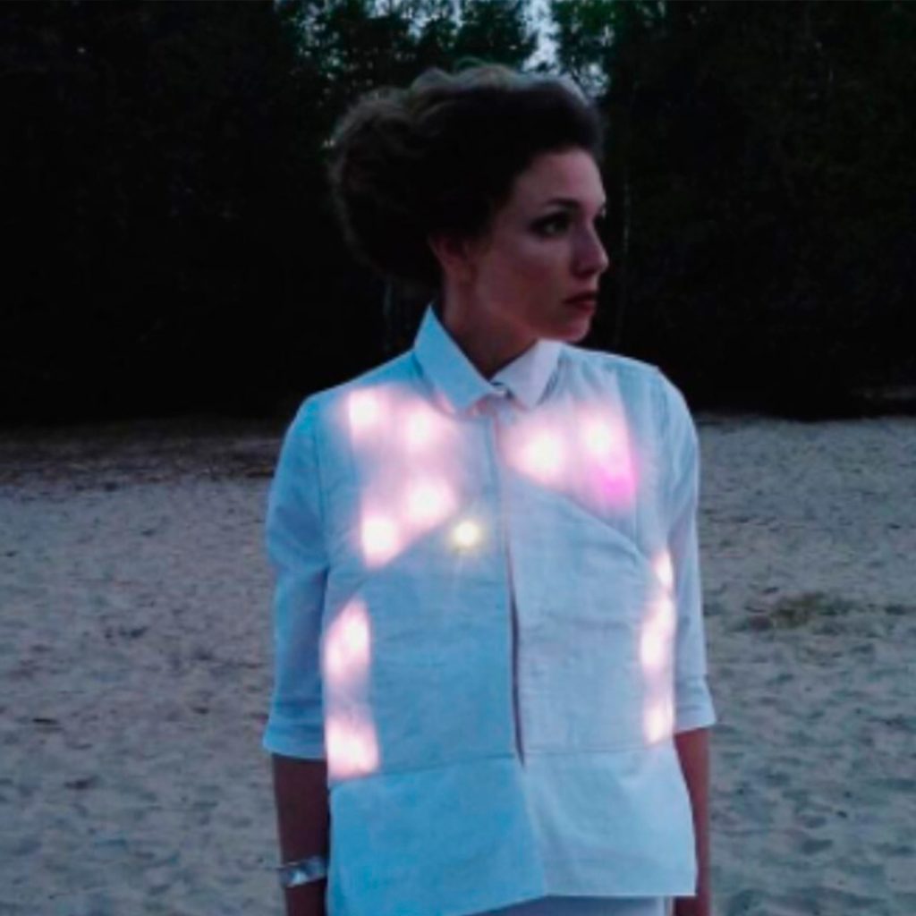 Femme portant un textile connecté, une chemise blanche illuminée et décorée par des leds.